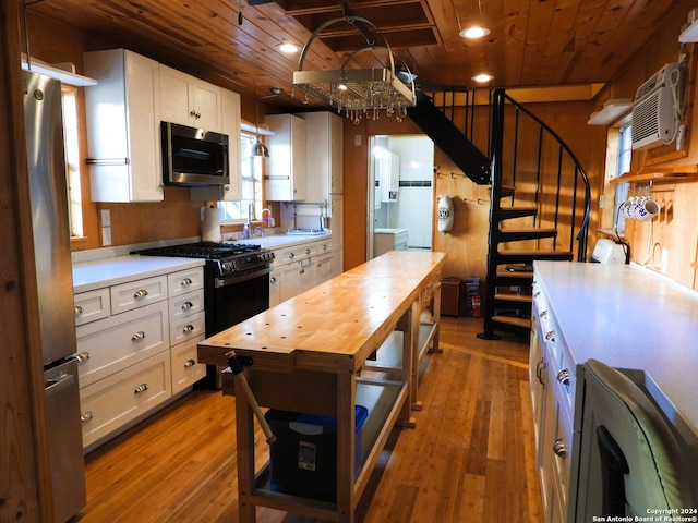 kitchen featuring appliances with stainless steel finishes, wood ceiling, white cabinetry, and light wood-type flooring