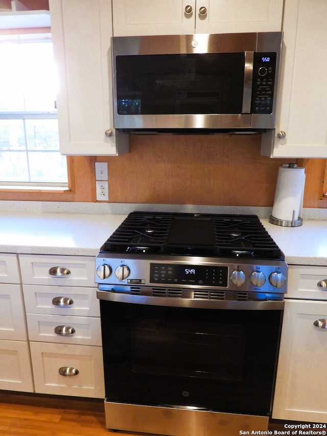 kitchen featuring white cabinets, stainless steel appliances, and light wood-type flooring