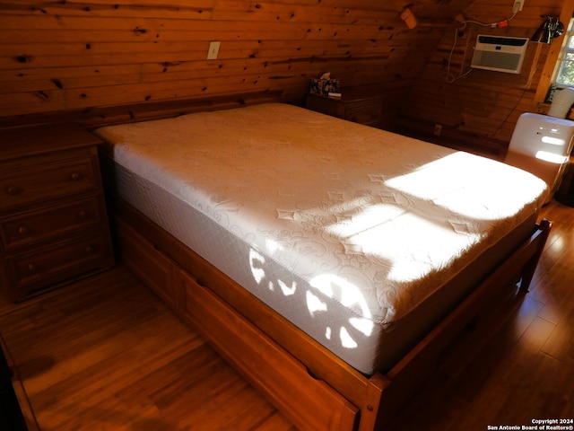 bedroom with dark wood-type flooring, a wall mounted air conditioner, and wood walls