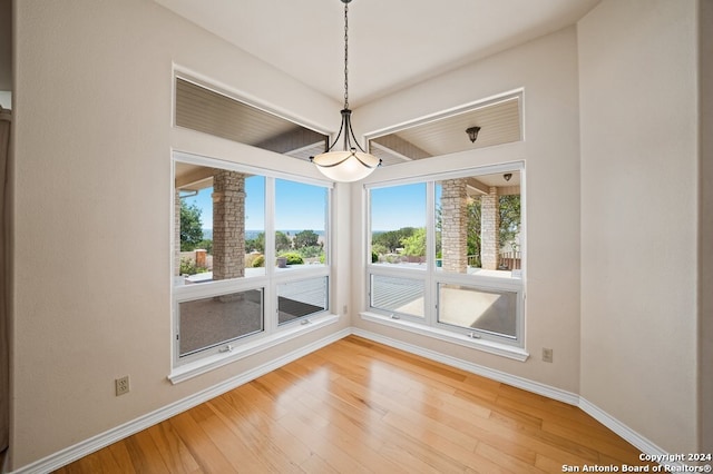 unfurnished dining area with hardwood / wood-style floors and beamed ceiling