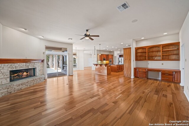 2029 Crown Rdg, Kerrville, TX 78028 - unfurnished living room with visible vents, recessed lighting, a glass covered fireplace, light wood-type flooring, and a ceiling fan
