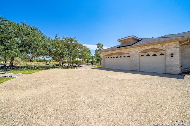 2029 Crown Rdg, Kerrville, TX 78028 - view of property exterior featuring driveway, roof with shingles, an attached garage, and brick siding