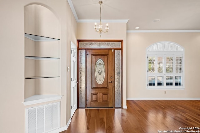 foyer entrance with an inviting chandelier, crown molding, and wood-type flooring