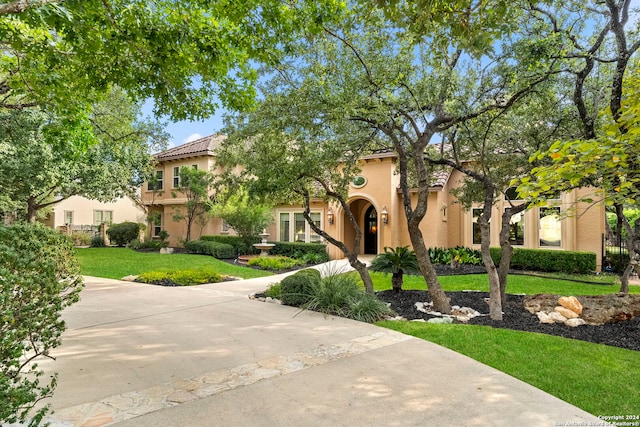 mediterranean / spanish house with a tile roof, a front lawn, and stucco siding