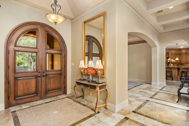 foyer with arched walkways, marble finish floor, crown molding, and baseboards