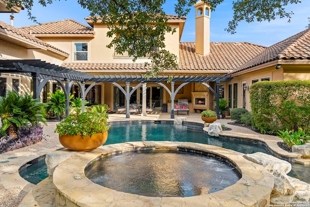 rear view of property featuring a tile roof, a patio, a chimney, stucco siding, and an in ground hot tub