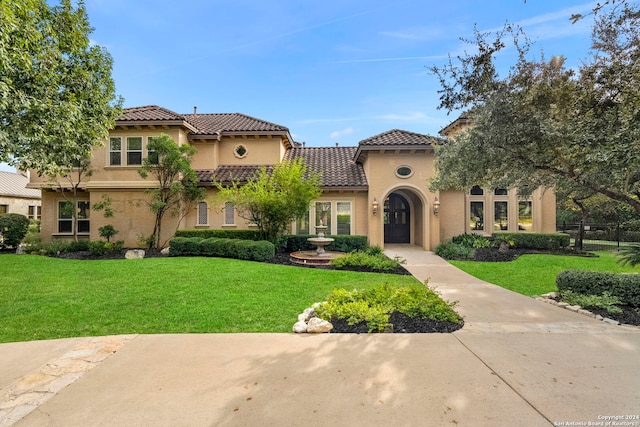 mediterranean / spanish house featuring a front yard, a tiled roof, and stucco siding