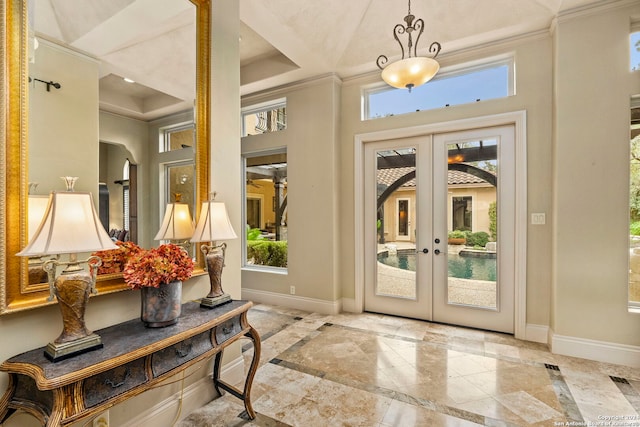 entryway featuring ornamental molding, french doors, a raised ceiling, and baseboards