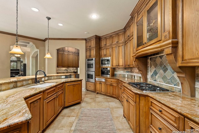 kitchen featuring appliances with stainless steel finishes, arched walkways, brown cabinets, and a sink