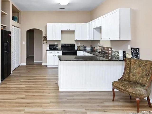 kitchen with light hardwood / wood-style floors, black appliances, kitchen peninsula, and white cabinets