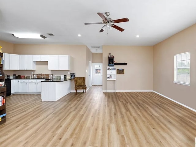 kitchen with kitchen peninsula, white cabinets, ceiling fan, light hardwood / wood-style floors, and sink