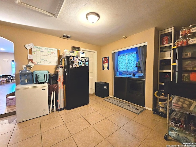 entrance foyer with a textured ceiling, light tile patterned flooring, and separate washer and dryer