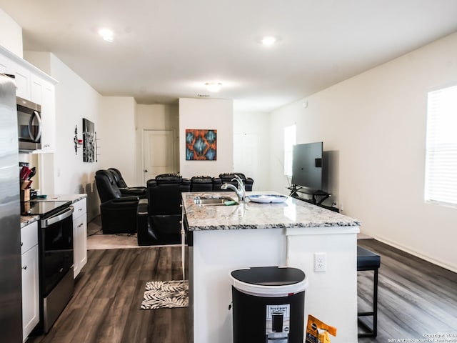 kitchen featuring appliances with stainless steel finishes, white cabinetry, a kitchen bar, and dark hardwood / wood-style floors