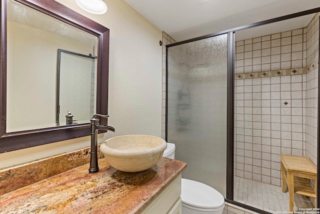 bathroom with a shower with door, vanity, toilet, and tile patterned flooring