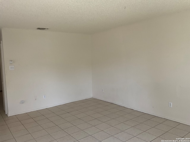 unfurnished room with a textured ceiling and light tile patterned flooring