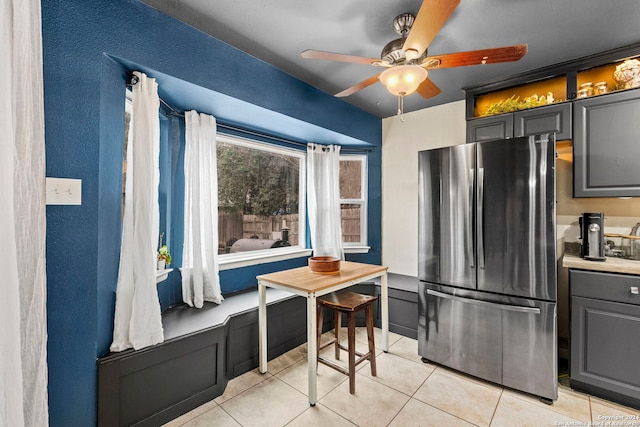 kitchen with gray cabinets, ceiling fan, stainless steel fridge, and light tile patterned flooring