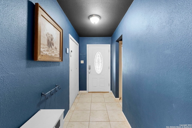 entryway with light tile patterned floors and a textured ceiling