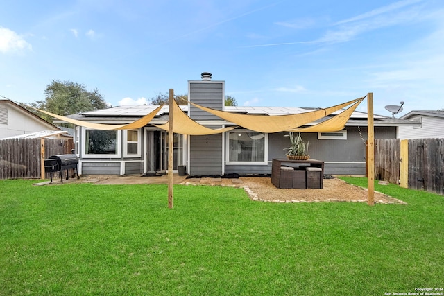 back of house featuring a lawn and solar panels