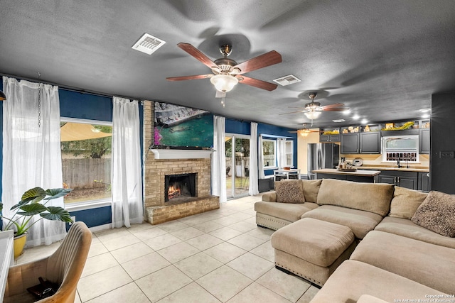 tiled living room with ceiling fan, a fireplace, a textured ceiling, and sink