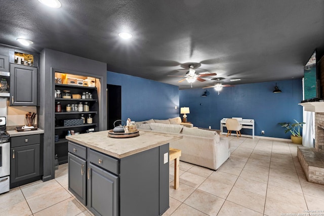 kitchen featuring a textured ceiling, a breakfast bar area, gray cabinets, a fireplace, and a kitchen island