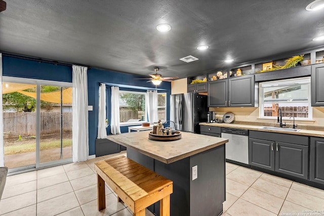 kitchen with a kitchen island, light tile patterned floors, sink, and appliances with stainless steel finishes