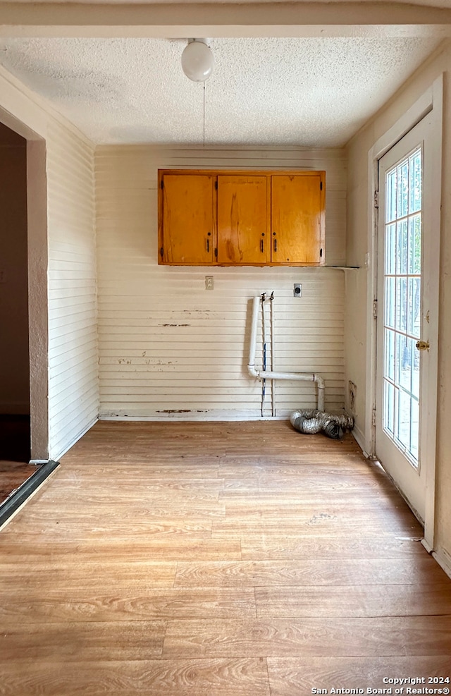 interior space featuring cabinets, light hardwood / wood-style flooring, a textured ceiling, and electric dryer hookup