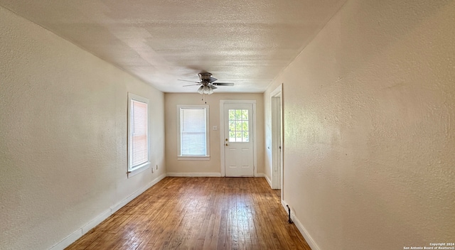 doorway featuring ceiling fan, hardwood / wood-style flooring, and a textured ceiling