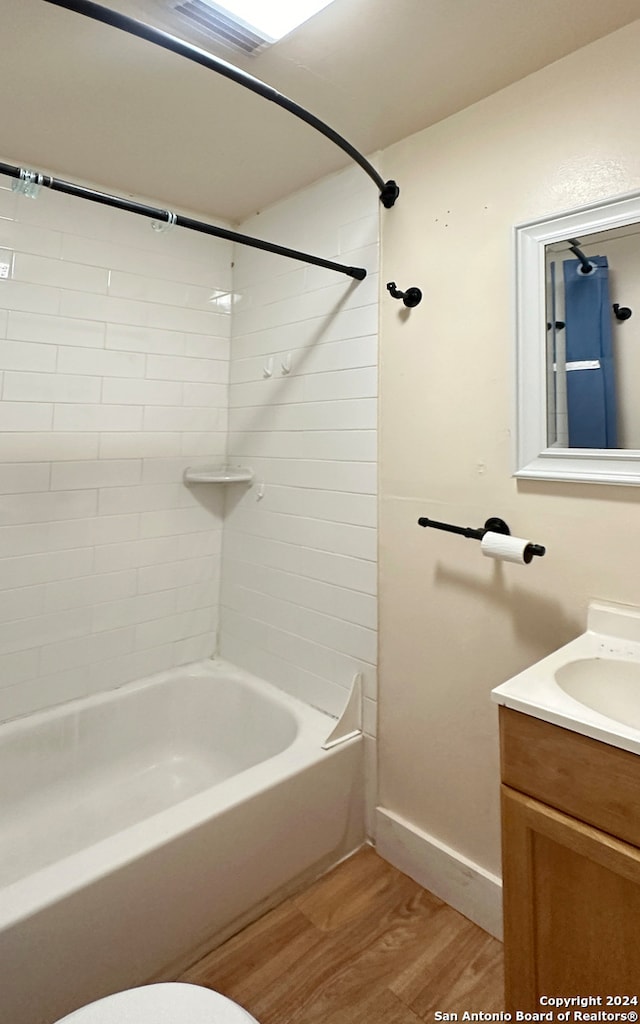 full bathroom with vanity, hardwood / wood-style floors, tiled shower / bath combo, and toilet