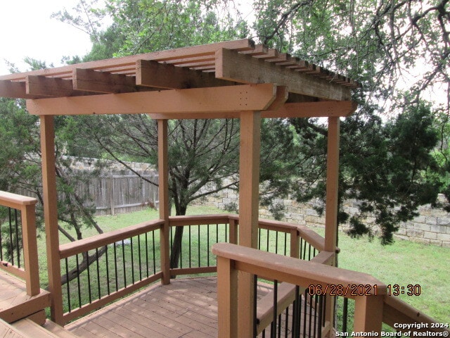 wooden deck with a lawn and a pergola