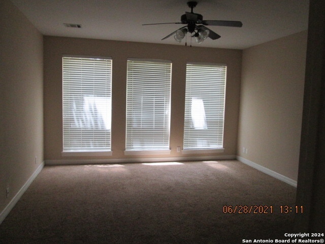 carpeted spare room with ceiling fan and plenty of natural light