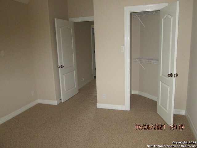 unfurnished bedroom with light colored carpet and a closet