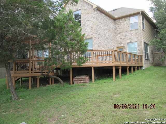 back of property with a wooden deck and a yard