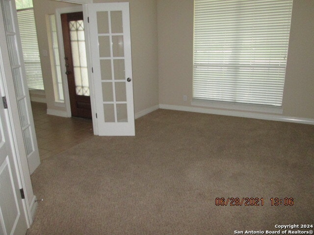 carpeted spare room featuring french doors