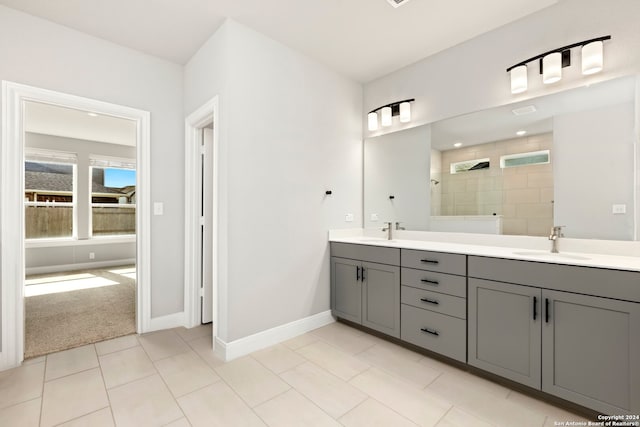 bathroom with a tile shower, tile patterned flooring, and vanity