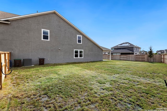 rear view of house with central AC and a yard