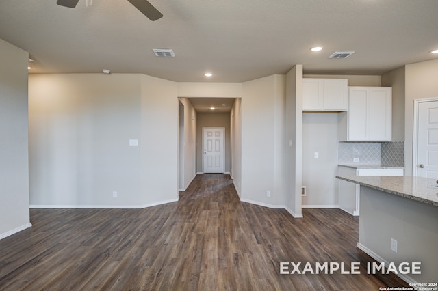 kitchen featuring decorative backsplash, white cabinets, ceiling fan, dark hardwood / wood-style floors, and light stone counters