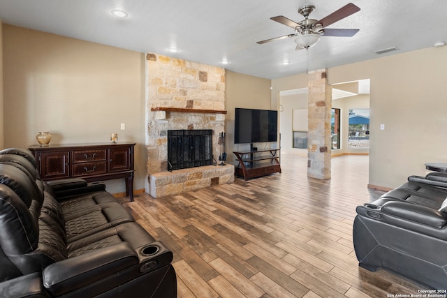 living room featuring a textured ceiling, a fireplace, light hardwood / wood-style floors, and ceiling fan