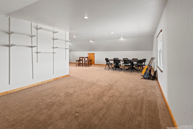 interior space with carpet, vaulted ceiling, and a textured ceiling