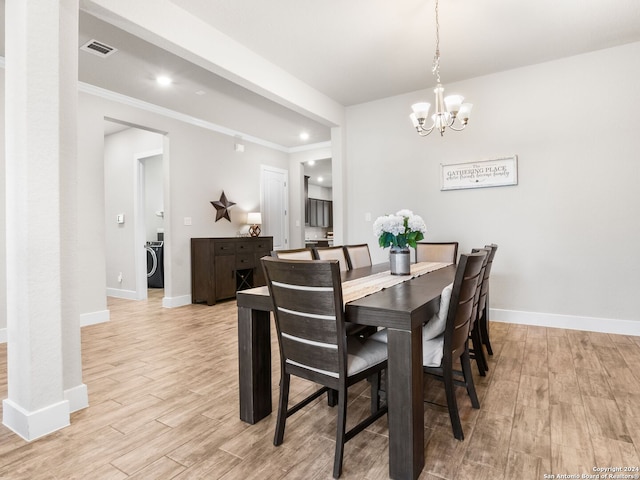 dining room with crown molding, light hardwood / wood-style flooring, an inviting chandelier, and washer / clothes dryer