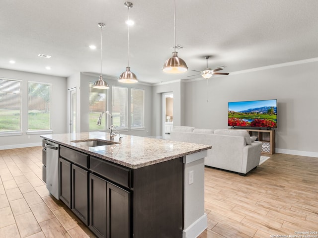 kitchen featuring a kitchen island with sink, hanging light fixtures, sink, light stone counters, and light hardwood / wood-style floors