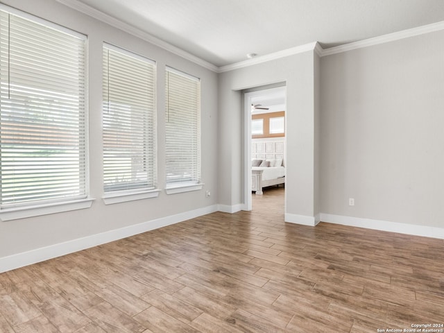 empty room with light hardwood / wood-style floors, ornamental molding, and a healthy amount of sunlight