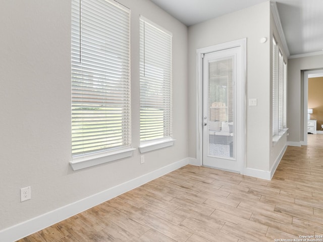 unfurnished room featuring ornamental molding and light wood-type flooring