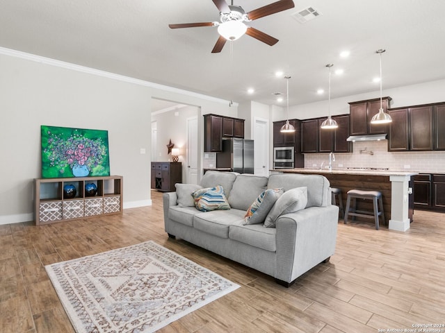 living room featuring crown molding, light hardwood / wood-style flooring, and ceiling fan