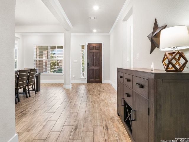 foyer with ornamental molding and light hardwood / wood-style floors