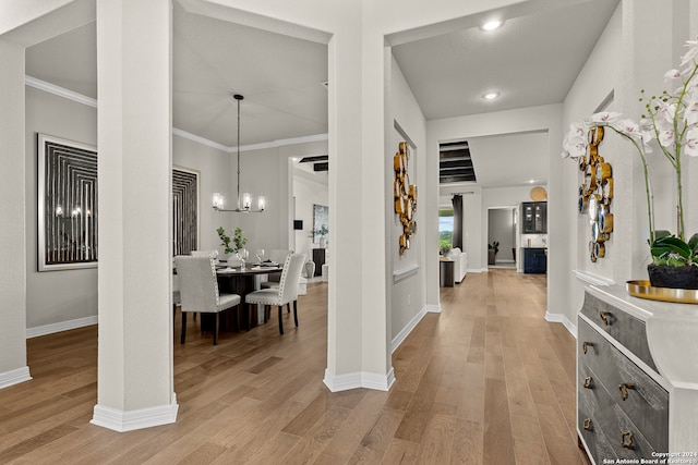 foyer entrance featuring ornamental molding, a notable chandelier, and light wood-type flooring