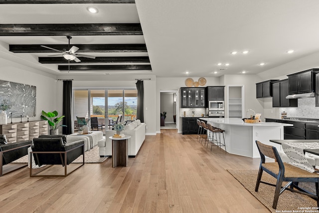 living room featuring light hardwood / wood-style flooring, beam ceiling, and ceiling fan