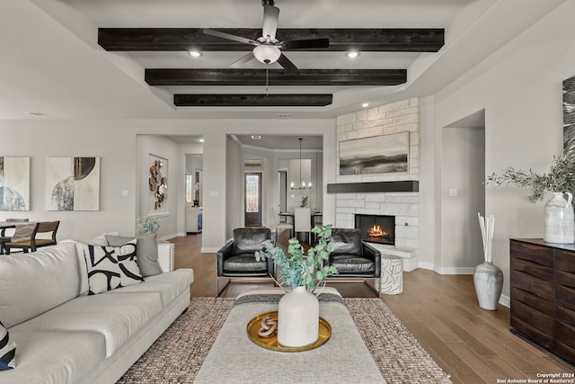 living room with beam ceiling, hardwood / wood-style floors, a fireplace, and ceiling fan with notable chandelier