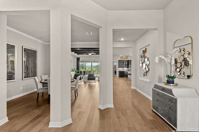 foyer with decorative columns, ornamental molding, and light wood-type flooring