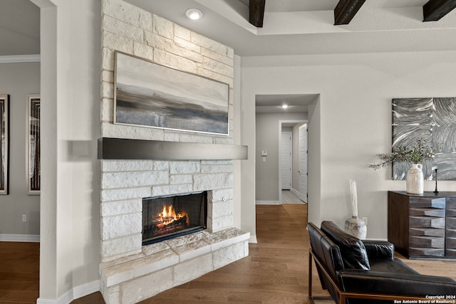 living room featuring ornamental molding, a stone fireplace, and wood-type flooring