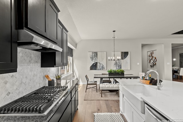 kitchen with decorative backsplash, light hardwood / wood-style flooring, white cabinets, an inviting chandelier, and appliances with stainless steel finishes